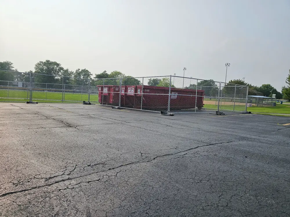 Fenced dumpster staging in park lot