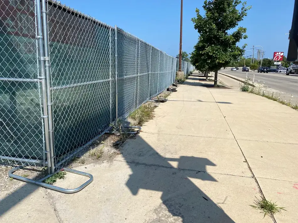 Green windscreen fence along a Chicago commercial sidewalk