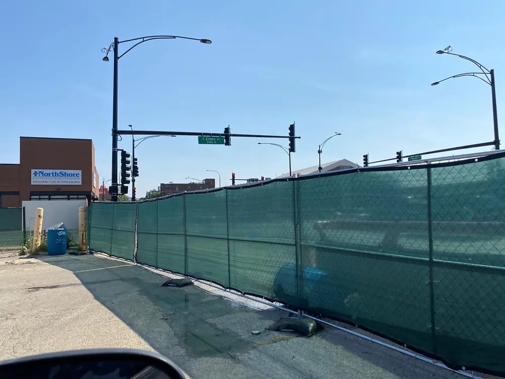 Green windscreen fence at corner construction lot, N Elston Ave Chicago