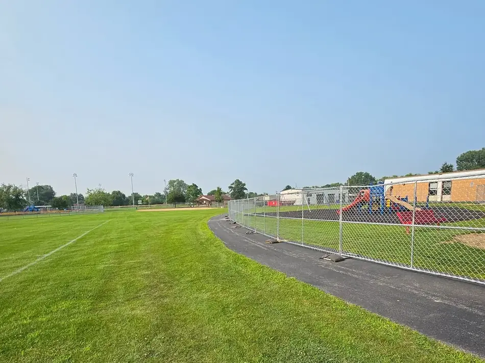 Temporary fence line protecting a baseball field and playground at a community park